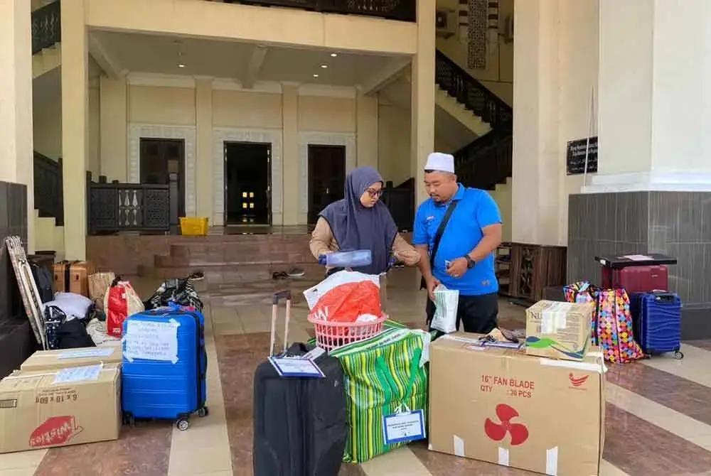 Siti Hajar (kiri) sebak semasa mengambil barangan milik adiknya, Mohammad Aqil di Masjid Hadhari, Jerteh pada Khamis.