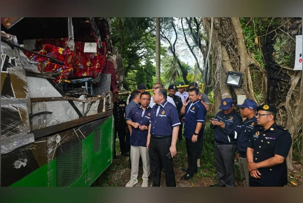 Anthony (dua dari kiri) meninjau keadaan bangkai bas yang terlibat dalam nahas tragis yang mengorbankan 15 nyawa penuntut UPSI di Gerik, Isnin lalu. 