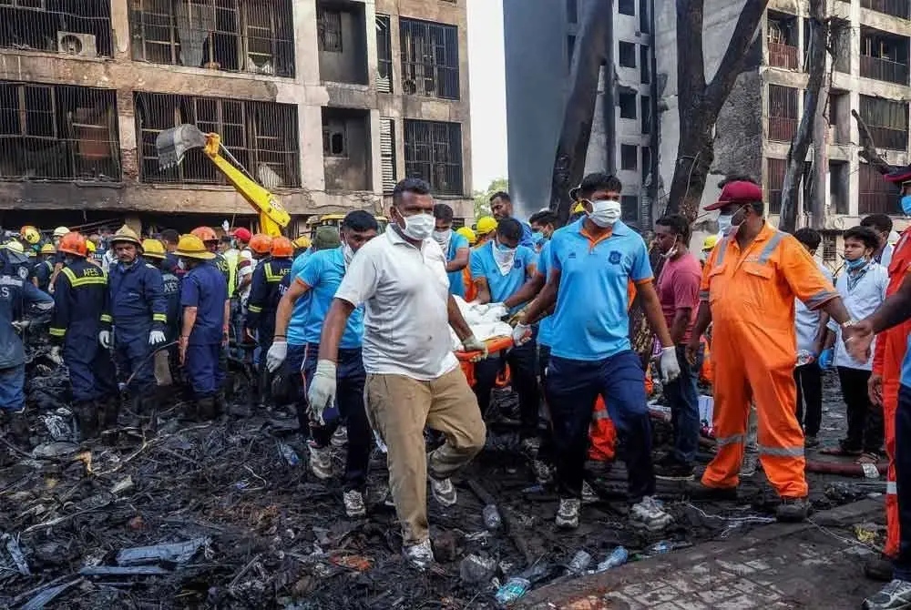 Pasukan penyelamat mengangkat mayat mangsa di lokasi nahas pesawat Air India di Ahmedabad. - AFP