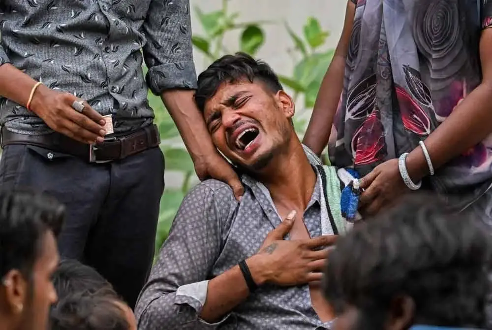 Kalpesh Patni (tengah) meratapi kematian adiknya, Akash, 14, di bilik mayat Hospital Ahmedabad.