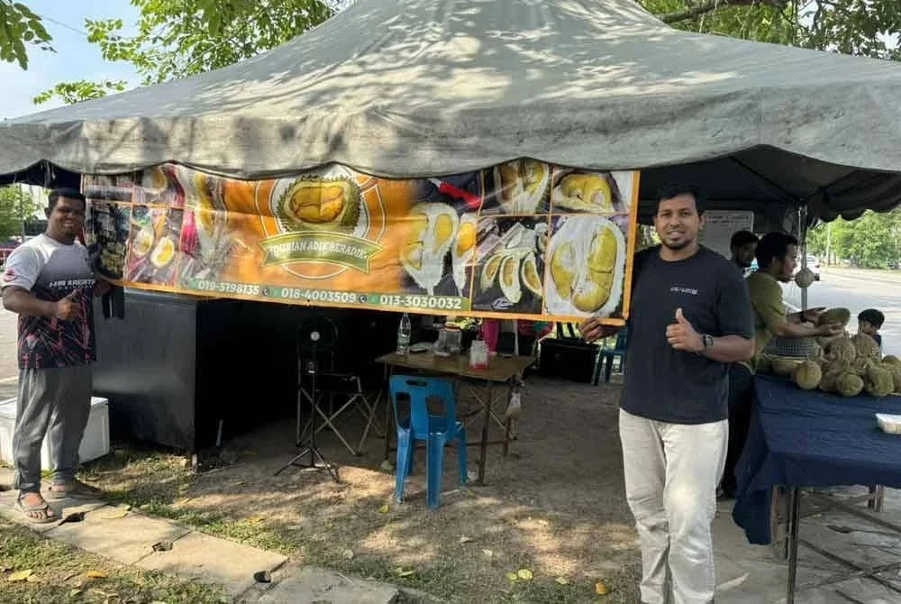 Mohamad Amin (kanan) di gerai durian yang diusahakan bersama rakannya.