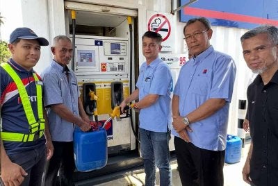 Muhammad Faiz Fadzil (tiga dari kanan) cuba mengisi minyak petrol di stesen minyak kontena mudah alih.