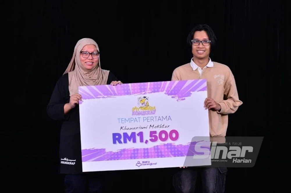 Firdaus (kiri) menyampaikan replika cek kepada Khawarizmi sewaktu Majlis Penyampaian Hadiah Sayembara Komikraf di Dewan Karangkraf pada Rabu.