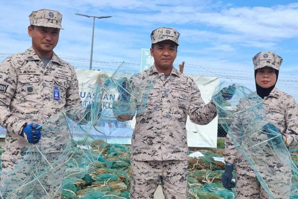 Mohd Hairil (tengah) menunjukkan bubu naga yang digunting sebagai gimik pelupusan bubu naga Zon Maritim Kuala Kurau pada Khamis.