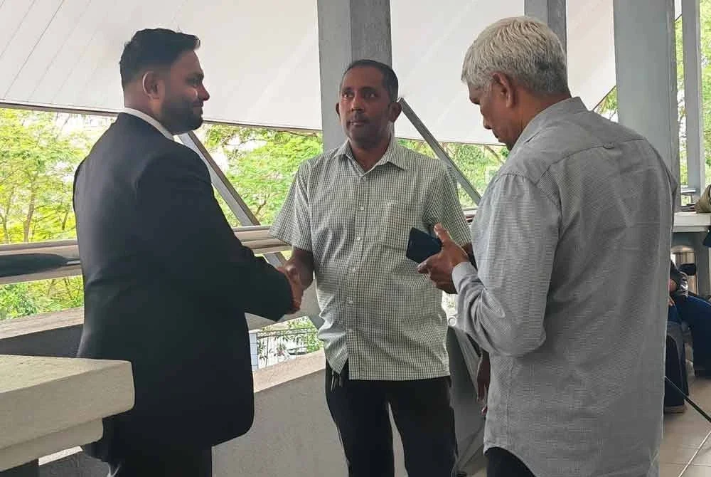 Arron (tengah) bertemu peguamnya di luar mahkamah.