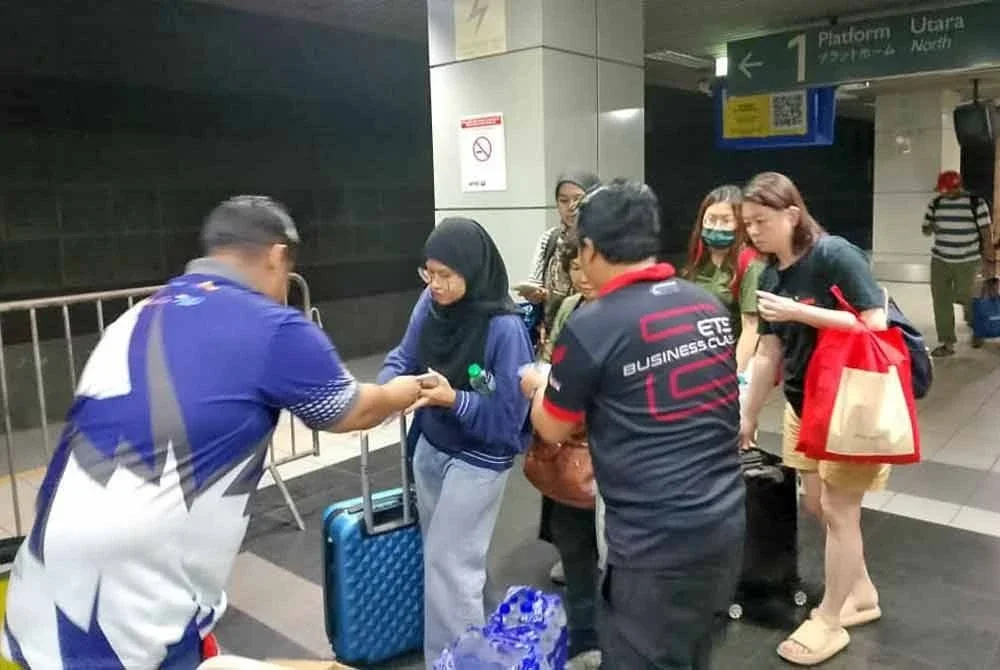 Petugas KTMB mengagihkan makanan dan minuman kepada penumpang terjejas akibat gangguan perkhidmatan tren KTMB antara Kampar dan Slim River pada Jumaat.