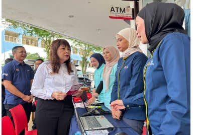 Hui Ying (dua dari kiri) bertanya mengenai Program SARA Kementerian Kewangan kepada petugas di Pasar Raya Mydin George Town pada Sabtu.