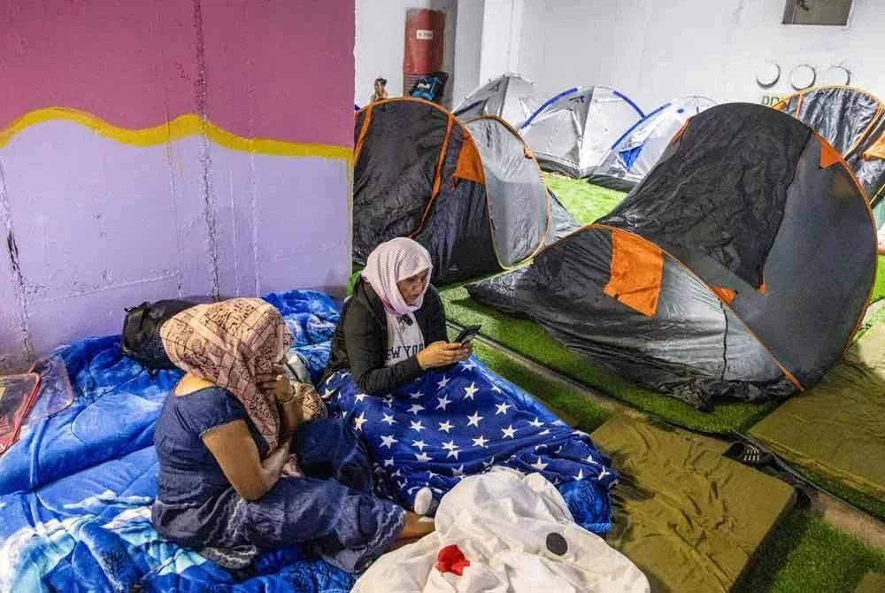 Pekerja asing dan ahli keluarga mereka berlindung di tempat letak kereta bawah tanah sebuah stesen bas di Tel Aviv pada 22 Jun 2025 kerana bimbang serangan peluru berpandu dari Iran. Foto AFP