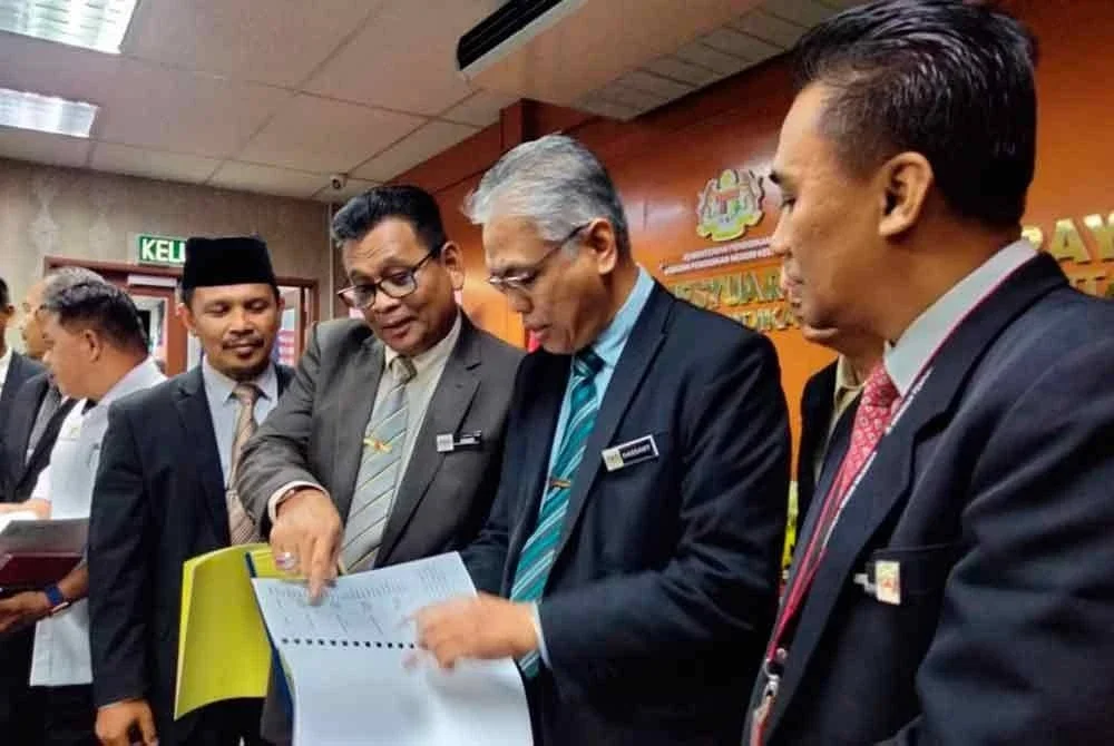 Mohd Hassany (dua dari kanan) melihat senarai calon STPM yang berjaya mendapat keputusan cemerlang.