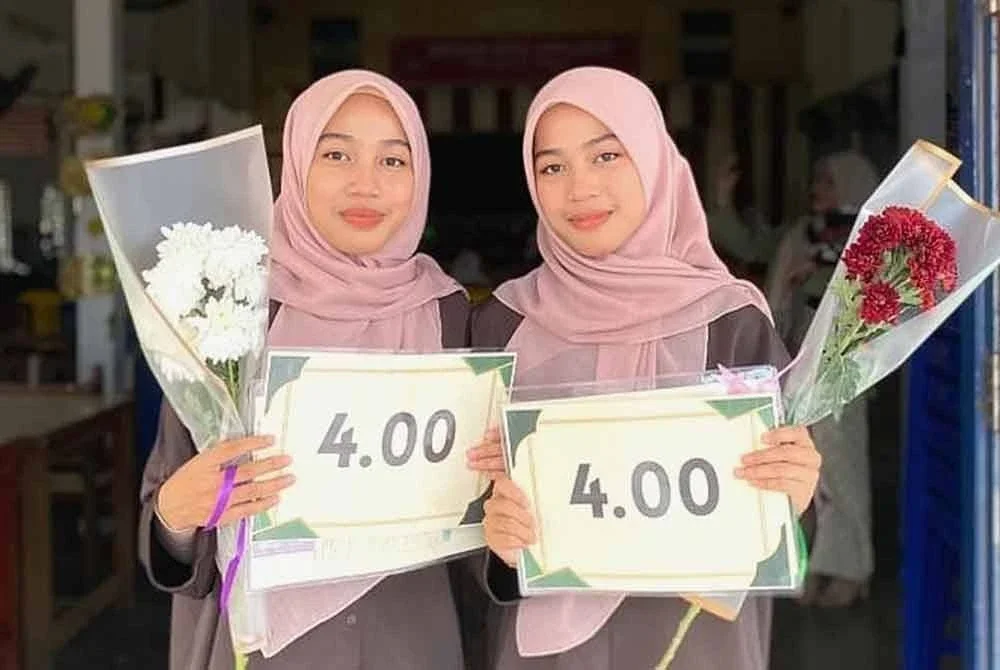 Amira Bazilah (kanan) bersama kembarnya, Amira Basirah ketika ditemui selepas menerima keputusan STPM di SMK Bukit Sawa, Marang, pada Selasa.