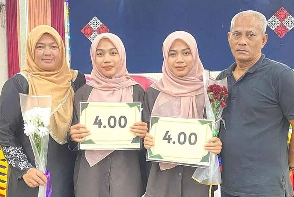 Amira Bazilah (dua dari kanan) bersama kembarnya, Amira Basirah merakam gambar bersama ibu bapa mereka selepas menerima keputusan STPM di SMK Bukit Sawa, Marang, pada Selasa.