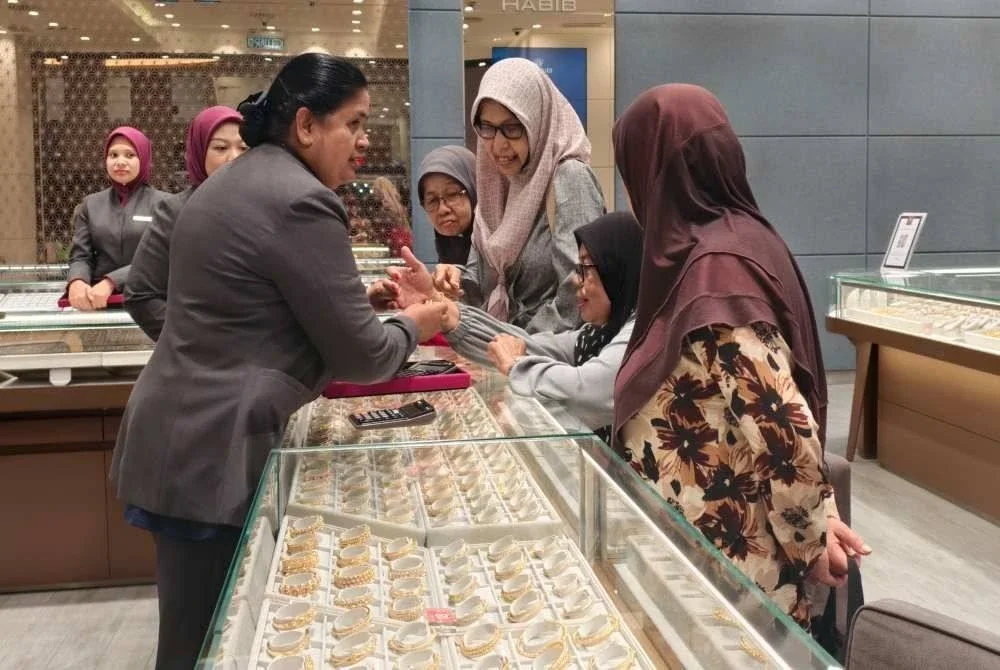 Pekerja sebuah kedai emas di Seremban 2 melayan pelanggan yang mahu membeli gelang tangan.