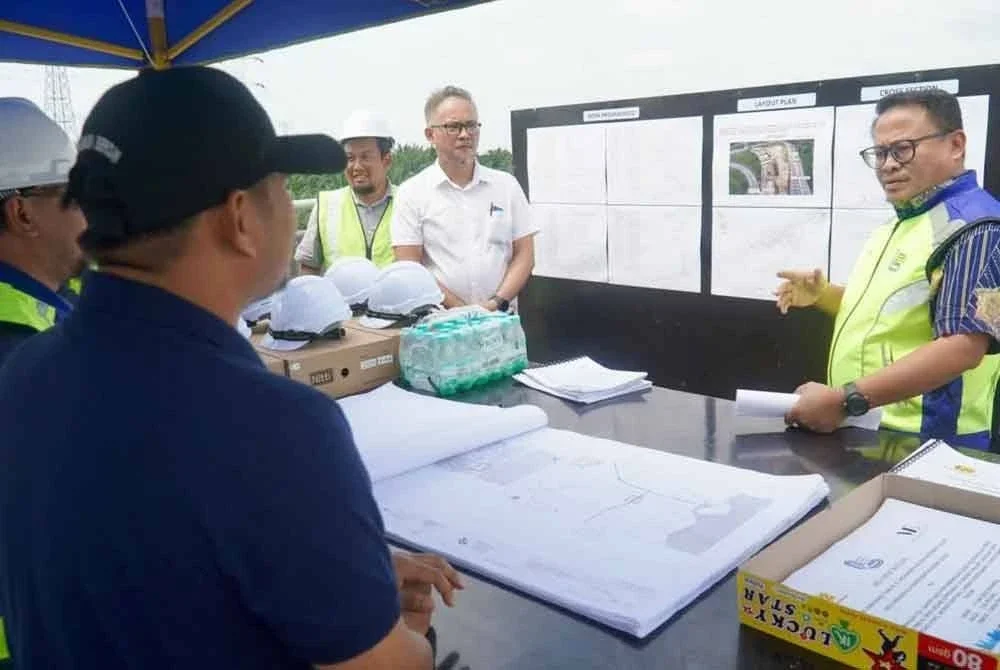 Mohamad Fazli (Kiri) diberi penerangan mengenai projek pembinaan struktur gerbang tol di Jejambat Meridin East berhampiran Plaza Tol Cahaya Baru Lebuhraya SDE, Pasir Gudang pada Rabu.