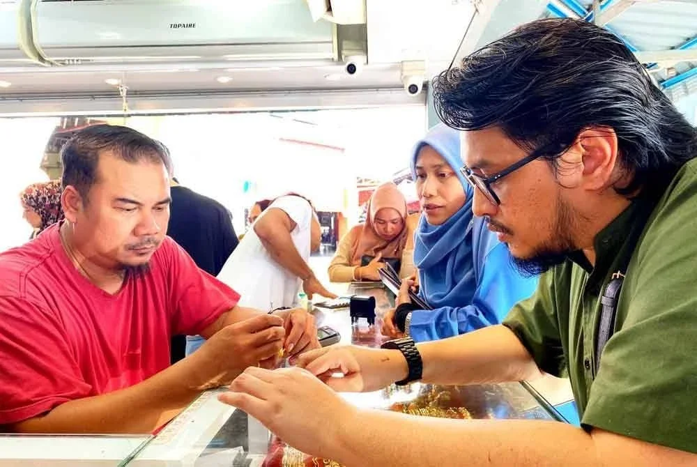 Peniaga kedai emas Mah Kampong Kito, Azuwadi (kiri) sibuk melayan pelanggan di kedainya yang terletak di Pasar Siti Khadijah, Kota Bharu.