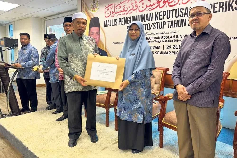 Wan Roslan (kiri) menyampaikan slip peperiksaan kepada Pengetua Maahad Tahfiz Al-Quran Darul Saadah Lilbanat, Hafizah Abdullah (tengah). FOTO SINAR HARIAN - ADILA SHARINNI WAHID