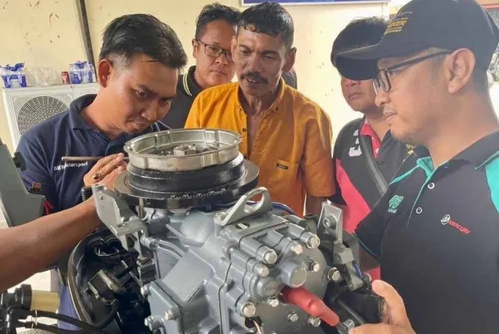 Para nelayan melihat enjin bot yang diterima mereka.