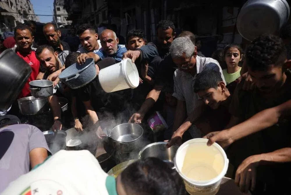 Penduduk Palestin berbaris untuk menerima makanan panas di pusat agihan makanan di Bandar Gaza. Foto AFP
