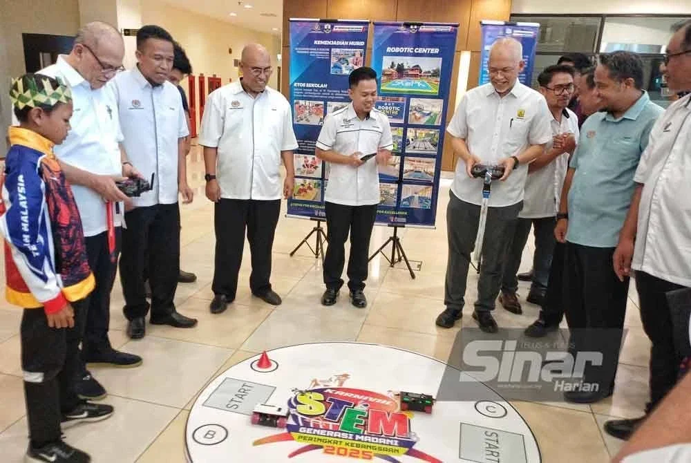 Wan Rosdy (dua hari kiri) mengawal robot menggunakan alat kawalan jauh yang dihasilkan murid orang asli selepas perasmian Karnival Apa Khabar Orang Kita dan Penyampaian Kecemerlangan Pendidikan Murid Orang Asli 2025 di Dewan Utama, Kompleks Yayasan Pahang, di sini pada Jumaat. Foto Sinar Harian.