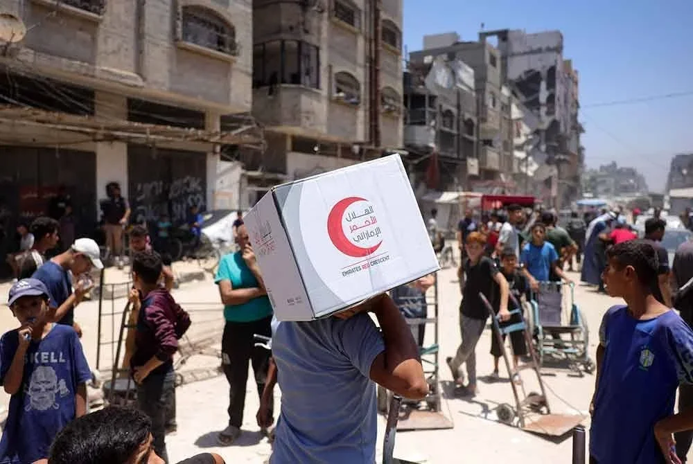 Seorang lelaki Palestin membawa bungkusan makanan yang disumbangkan oleh Bulan Sabit Merah Emiriah Arab Bersatu dari pusat agihan di Bandar Gaza. Foto AFP