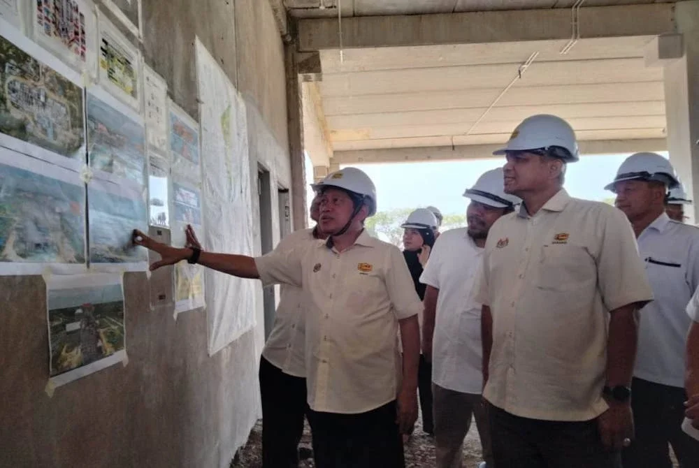 Ahmad (kiri) melihat plan bangunan ketika lawatan kerja rasmi ke Projek UMK, Pembinaan Bangunan Kompleks Fakulti Keusahawanan, Kampus Bachok pada Sabtu.