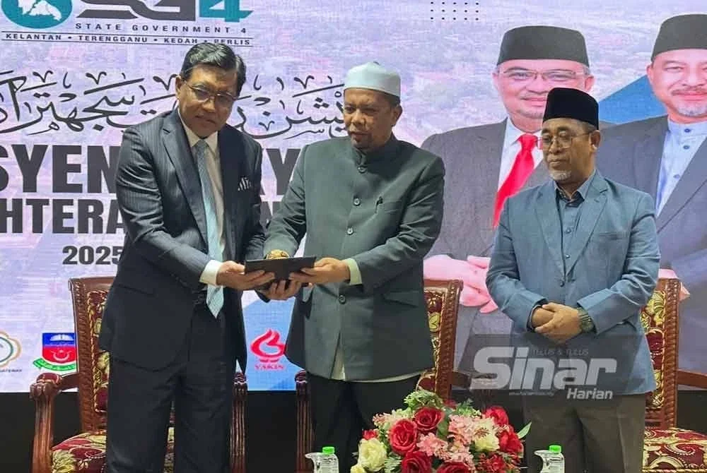 Wan Roslan (tengah) menyampaikan replika cek kepada Ahli Dewan Undangan Negeri Pasir Tumboh, Datuk Abdul Rahman Yunus (kanan).