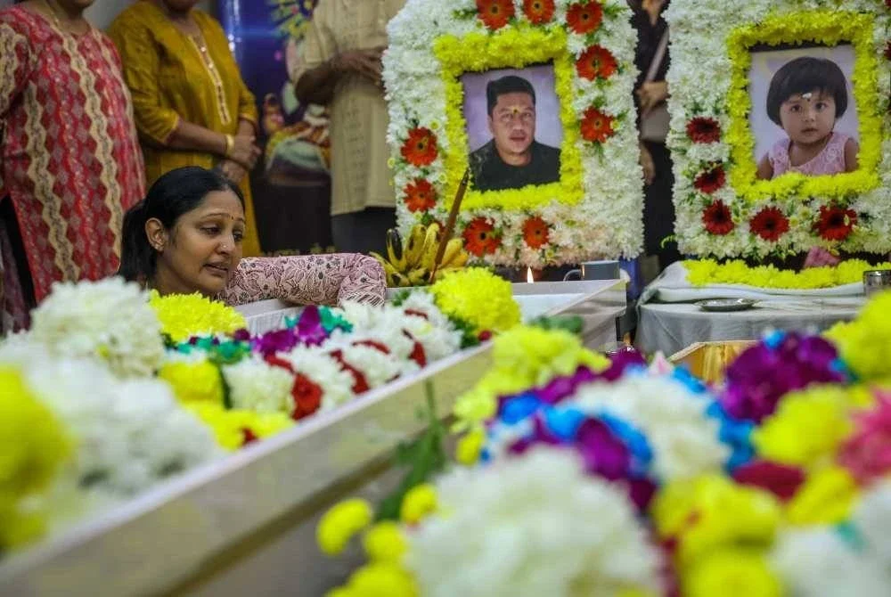 Sanggetha (kiri) memberi penghormatan terakhir terhadap mendiang suami dan anaknya di kediaman mereka dekat Taman Bayu Aman pada Isnin. Foto Bernama 