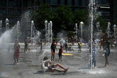 Pengunjung menyejukkan badan mereka dengan air pancut di Taman Awam Andre-Citroen di Paris.