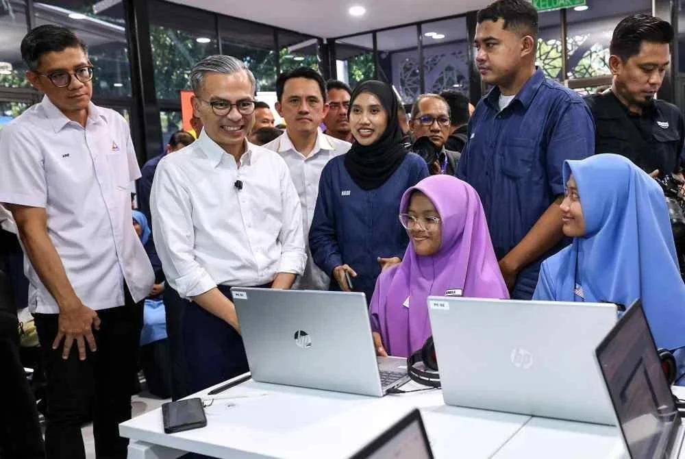 Fahmi (dua, kiri) beramah mesra dengan para pelajar sekolah ketika melakukan lawatan di Pusat Ekonomi Digital (NADI) Kubang Semang pada Isnin. Foto Bernama