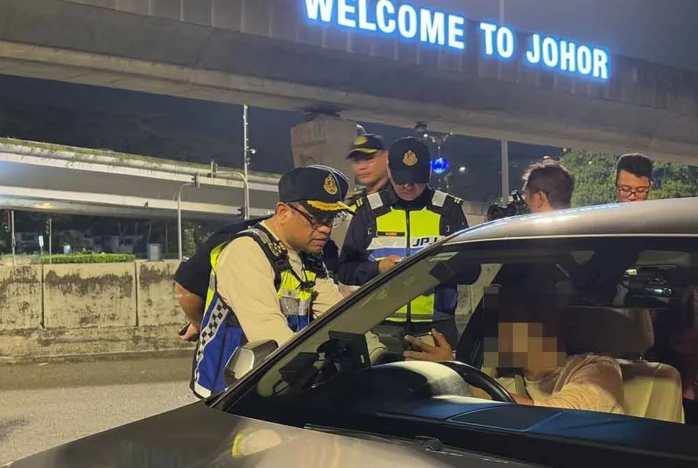 Aedy Fadly (kiri) menjelaskan kepada pemilik kenderaan mengenai penguatkuasaan VEP di laluan keluar Kompleks Kastam, Imigresen dan Kuarantin (CIQ) Bangunan Sultan Iskandar (BSI), tengah malam Isnin.