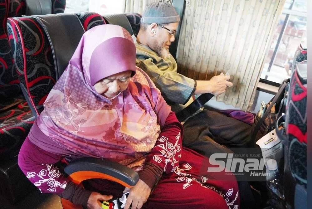 Roslee dan isterinya, Eshah Long, 60, memakai tali pinggang sebelum bas dinaiki mereka memulakan perjalanan dari Kuala Lumpur ke Parit Buntar pada Selasa. Foto Sinar Harian ROSLI TALIB