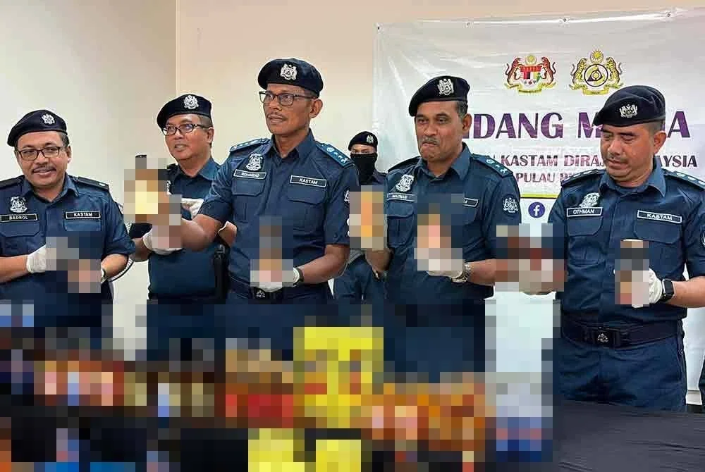 Rohaizad (tengah) bersama pegawai kanan JKDM Pulau Pinang menunjukkan rokok dan minuman keras yang dirampas.