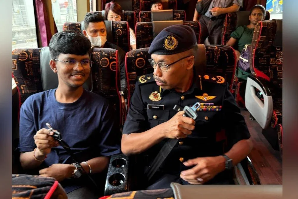 Hanif (kanan) ketika menjalankan pemeriksaan pematuhan pemakaian tali pinggang keledydi sebuah bas di Terminal One Seremban pada Rabu.