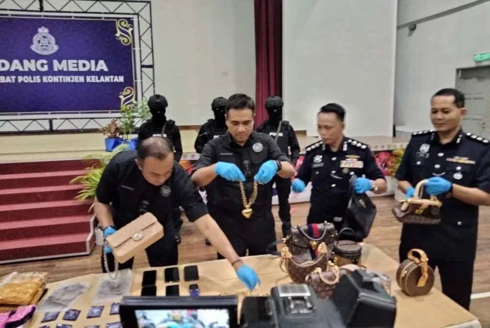 Mat Zani@Mohd Salahuddin (dua dari kiri) menunjukkan barang kemas dan beg berjenama mewah yang dirampas daripada sindiket dadah.
