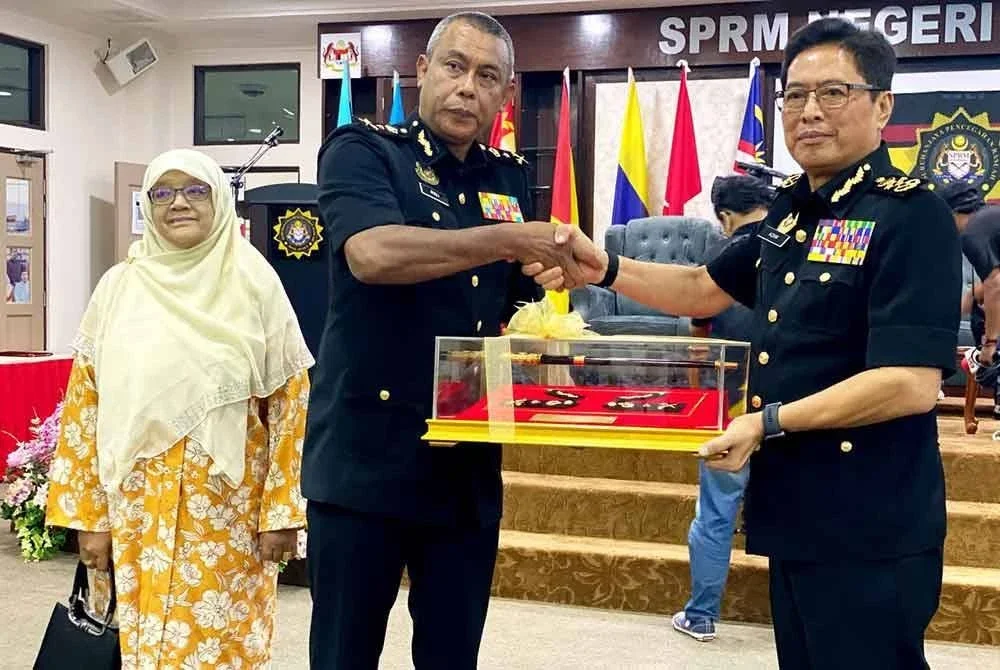 Azam (kanan) menyampaikan cenderamata kepada Rosli pada Majlis Persaraan di Pejabat SPRM Kelantan, Kota Bharu pada Khamis.