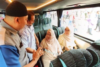 Mohammad Fakhri (dua dari kiri) menunjukkan tali pinggang keledar yang disediakan pengendali bas di tempat duduk penumpang.