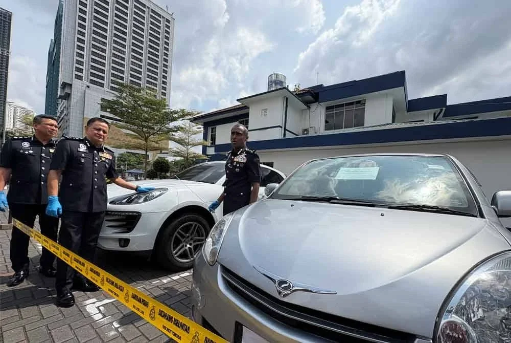 Kumar (tengah) menunjukkan dua kenderaan milik ahli sindiket yang disita.