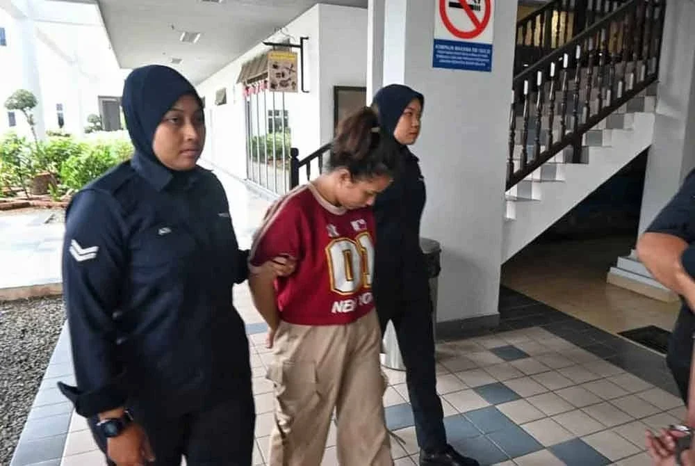 Jasila (tengah) yang sedang mengandung dibawa keluar dari Mahkamah Majistret Melaka pada Jumaat.