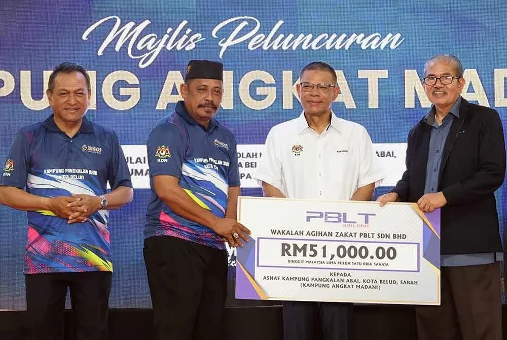 Saifuddin Nasution (dua dari kanan) menyerahkan sumbangan Wakalah Agihan Zakat PBLT Sdn Bhd kepada Ketua Kampung Pangkalan Abai, Saipudin Nbatamin (tiga dari kanan) pada Majlis Peluncuran Kampung Angkat Madani Kementerian Dalam Negeri di Kampung Pangkalan Abai pada Jumaat. Foto Bernama