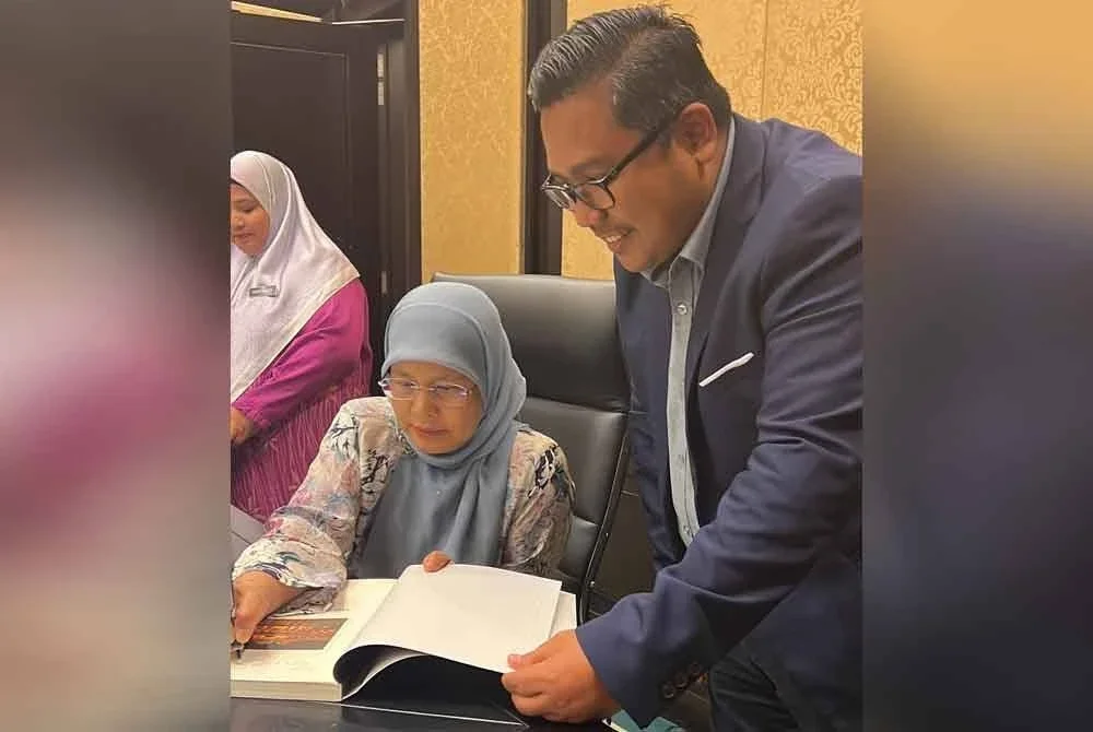 Zamri (kanan) mendapatkan tandatangan kenang-kenangan Tengku Maimun ketika sesi santai bersama media di pejabat Ketua Hakim Negara pada 2023.