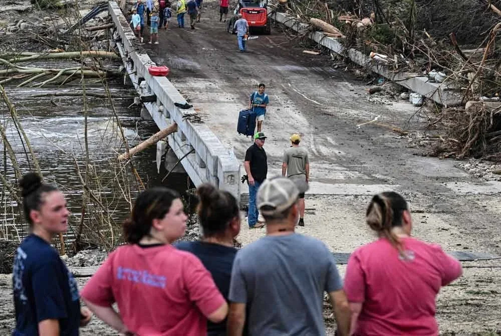 Orang ramai melihat dengan penuh perhatian ketika pihak penguat kuasa undang-undang dan sukarelawan terus mencari orang hilang berhampiran Kem Mystic. Foto AFP