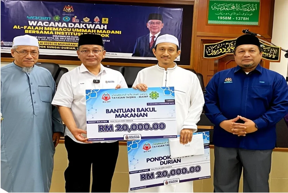 Mohd Na'im (dua,kiri) menyampaikan cek sumbangan kepada wakil pondok pada Wacana Dakwah Al-Falah Memacu Ummah Madani Bersama Institusi Pondok di Pondok Sungai Durian, Kuala Krai pada Ahad.
