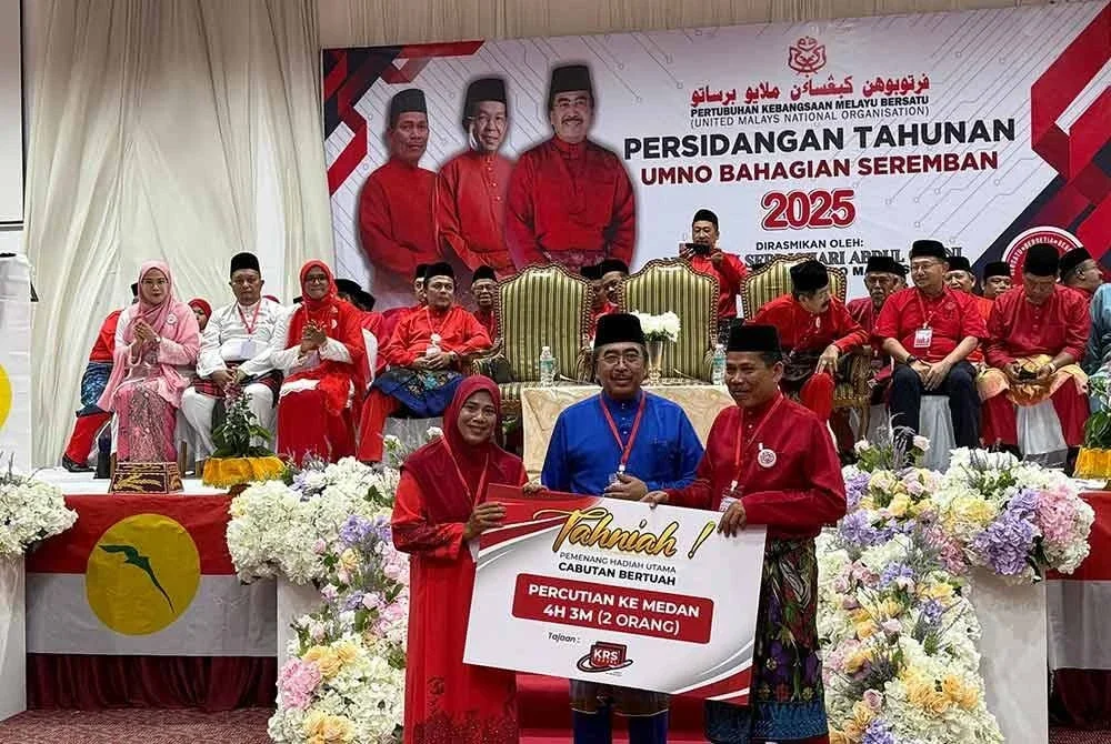 Johari (tengah) menyampaikan hadiah cabutan bertuah kepada perwakilan pada Mesyuarat UMNO Bahagian Seremban pada Ahad.