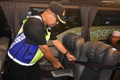 Anggota JPJ memeriksa keadaan tali pinggang keledar yang disediakan dalam sebuah bas ekspres.
