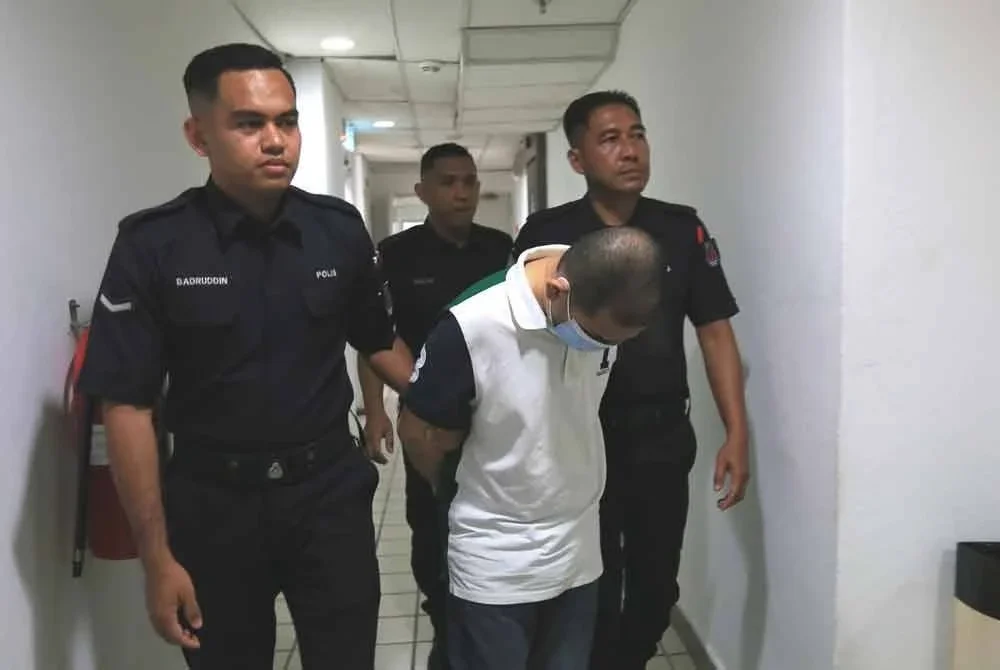 Tertuduh (tengah) dihadapkan di Mahkamah Tinggi di Kuala Terengganu pada Rabu.