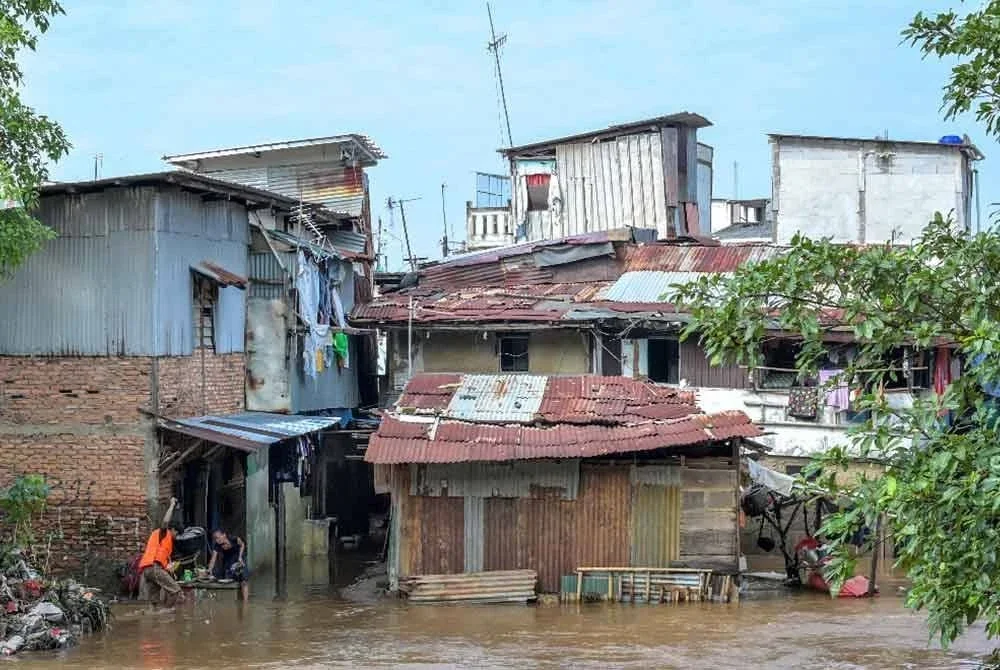 Penduduk cuba menyelamatkan harta benda daripada ditenggelami banjir yang melanda Jakarta akibat hujan lebat pada Ahad. Foto: AFP