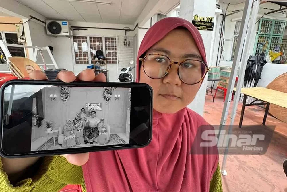 Nor Hanani Mawaddah menunjukkan gambar abangnya sekeluarga yang maut dalam tragedi Sungai Korok.