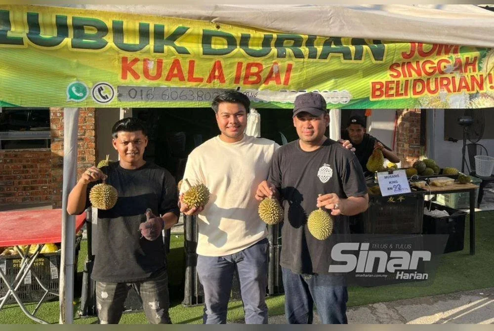 Shahril (kanan) bersama Muhd Aminuddin (tengah) menunjukkan durian yang dijual di pusat bandar Kuala Terengganu.