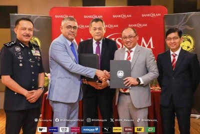 Mizan (dua dari kanan) dan Noor Azman bertukar dokumen selepas majlis yang berlangsung di Menara Bank Islam pada Jumaat. Foto: FAM