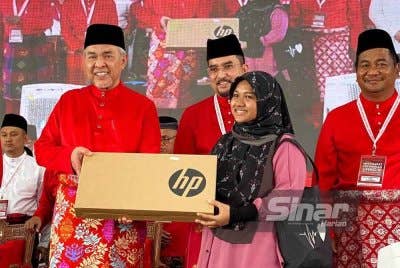 Ahmad Zahid (kiri) menyampaikan sumbangan komputer riba kepada pelajar cemerlang selepas merasmikan Mesyuarat Perwakilan UMNO Bahagian Tanah Merah pada Jumaat. Foto SINAR HARIAN/HAZELEN LIANA KAMARUDIN