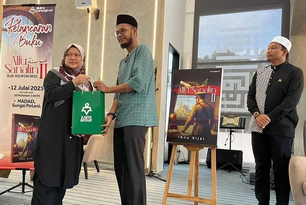 Roziyana (kiri) menyerahkan cenderahati kepada Ibnu Rijal (dua dari kanan) sambil disaksikan Mohammad Yaakub Yusra (kanan) sempena pelancaran buku Alfu Sanatin II.